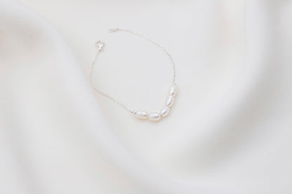  a white pearl beaded bracelet with gold accents on white background.