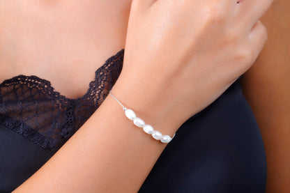 A woman wearing a white pearl beaded bracelet with gold accents on her wrist.