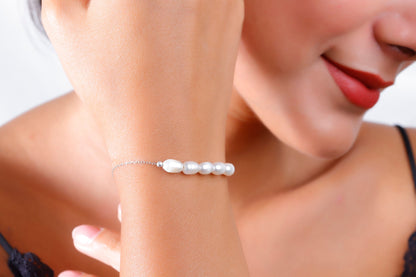 A woman wearing a white pearl beaded bracelet with gold accents on her wrist.