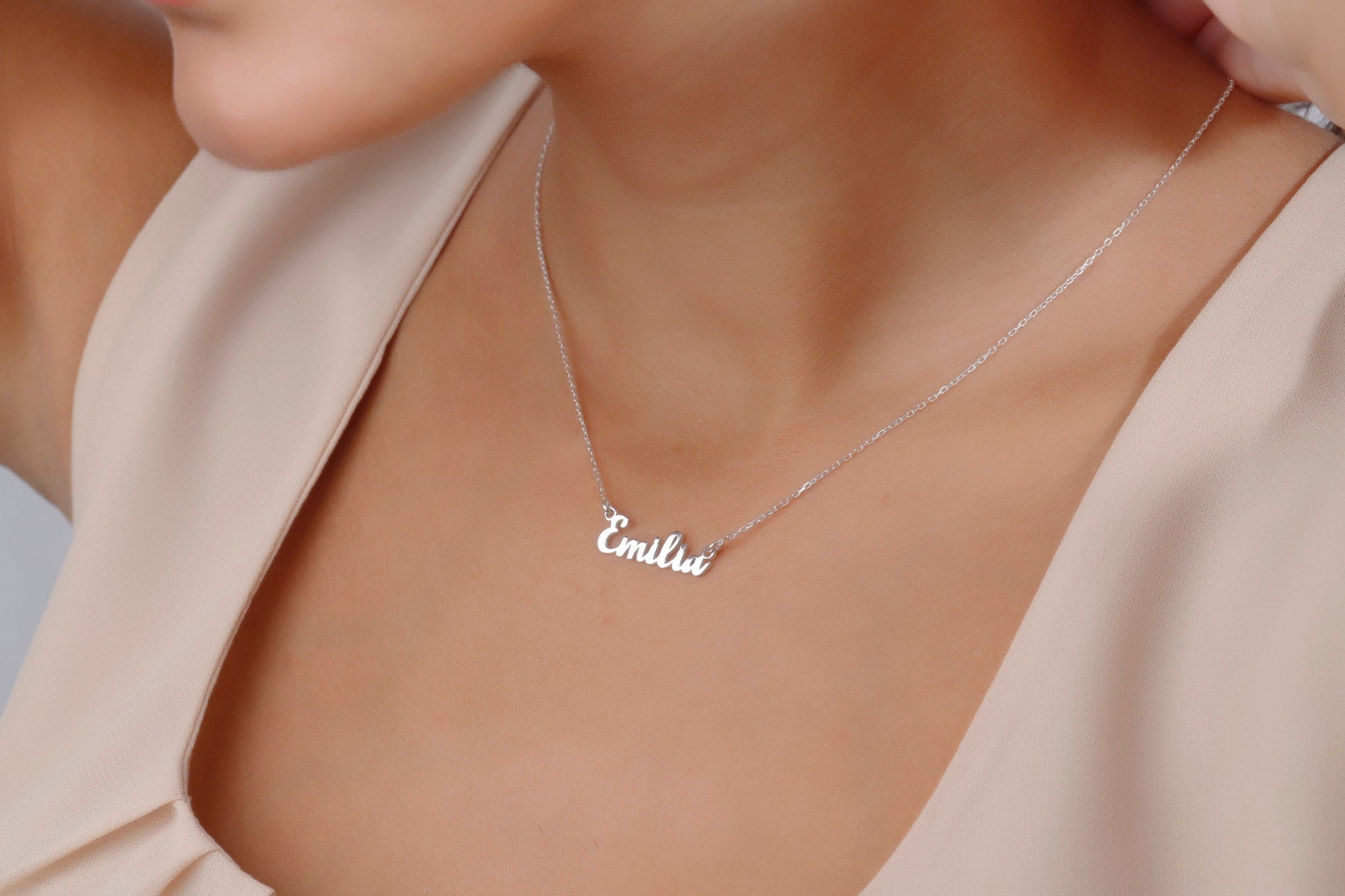 Necklace with 'Emilia' pendant on a person wearing a beige top