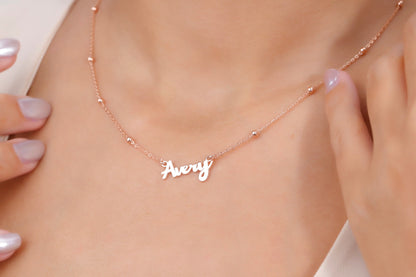 Rose gold necklace with 'Avery' pendant on a person's neck