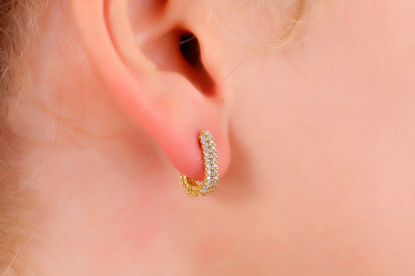 Gold hoop earring worn on a person's ear