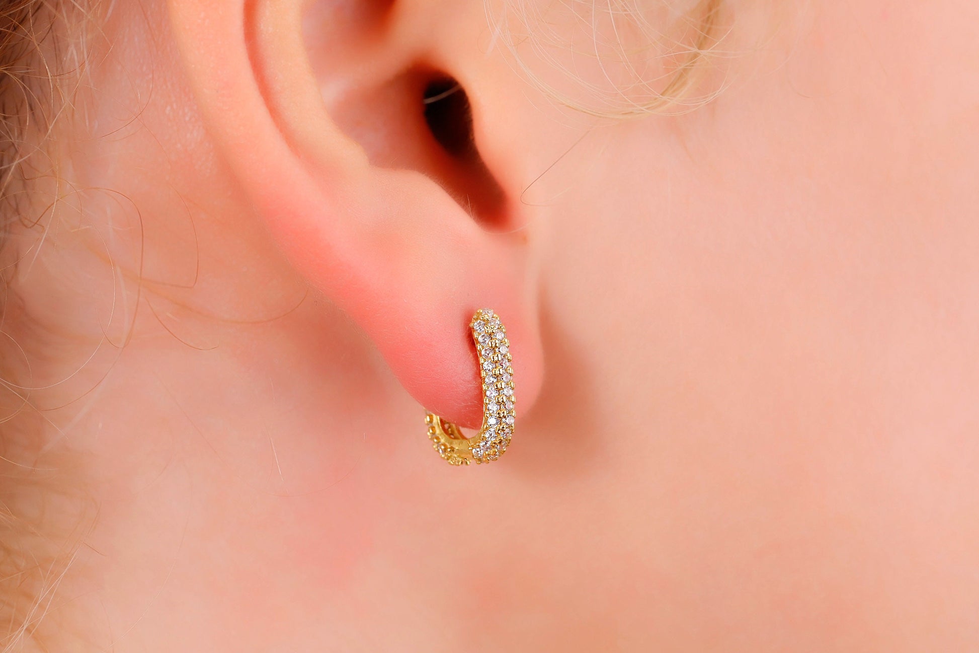 Gold hoop earring worn on a person's ear