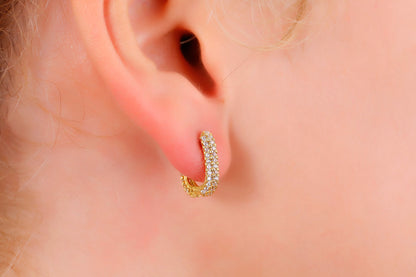 Gold hoop earring worn on a person's ear