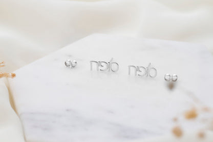 Pair of silver earrings written in Hebrew on a white background