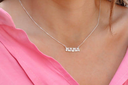 A close-up image of a woman wearing a silver-colored necklace with a 3D balloon-shaped pendant that reads 'mama'.