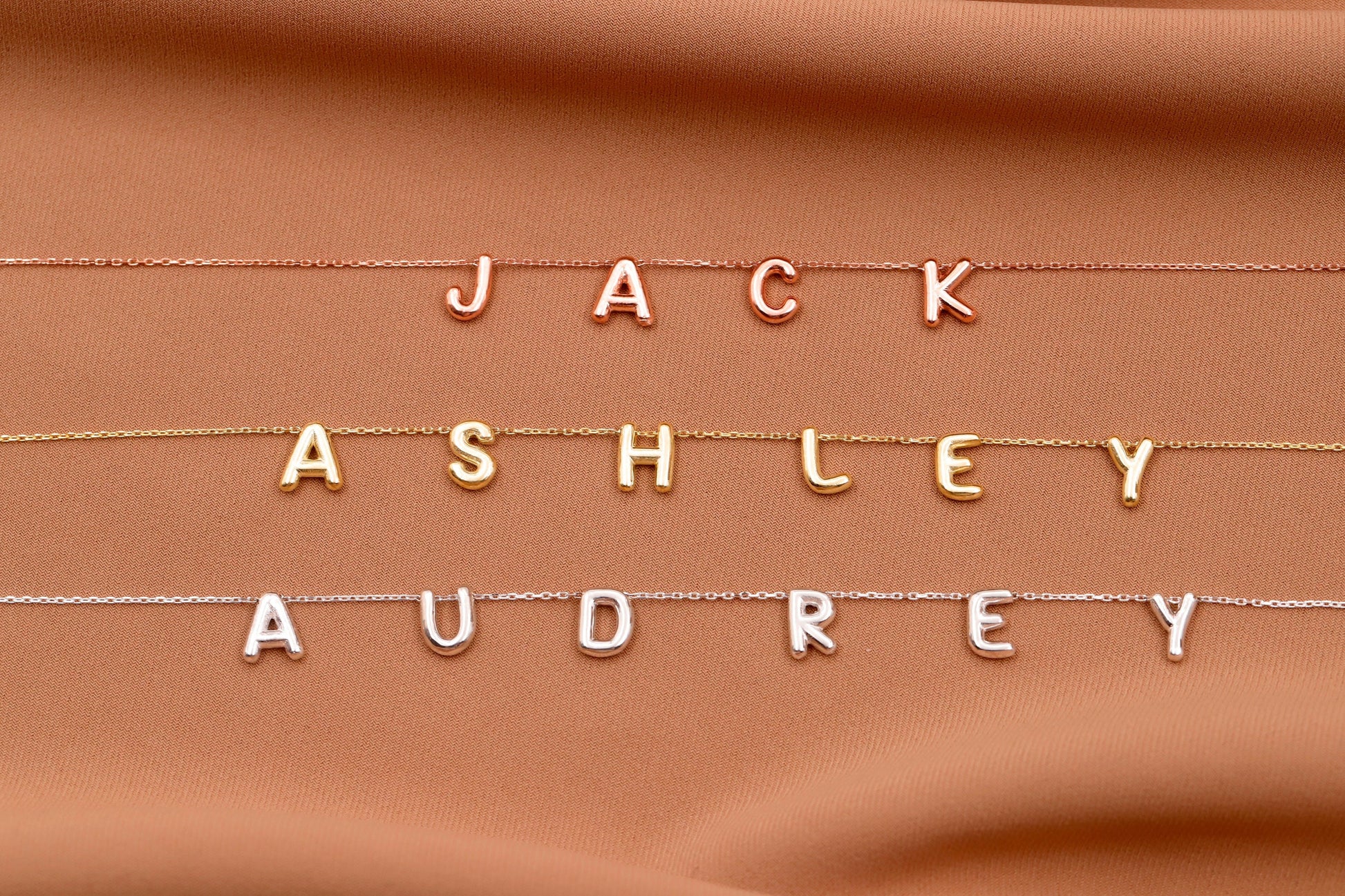 Gold letters spelling 'JACK ASHLEY AUDREY' on a brown fabric background