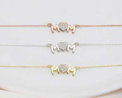 Three 'MOM' bracelets in gold, silver, and rose gold on a white background