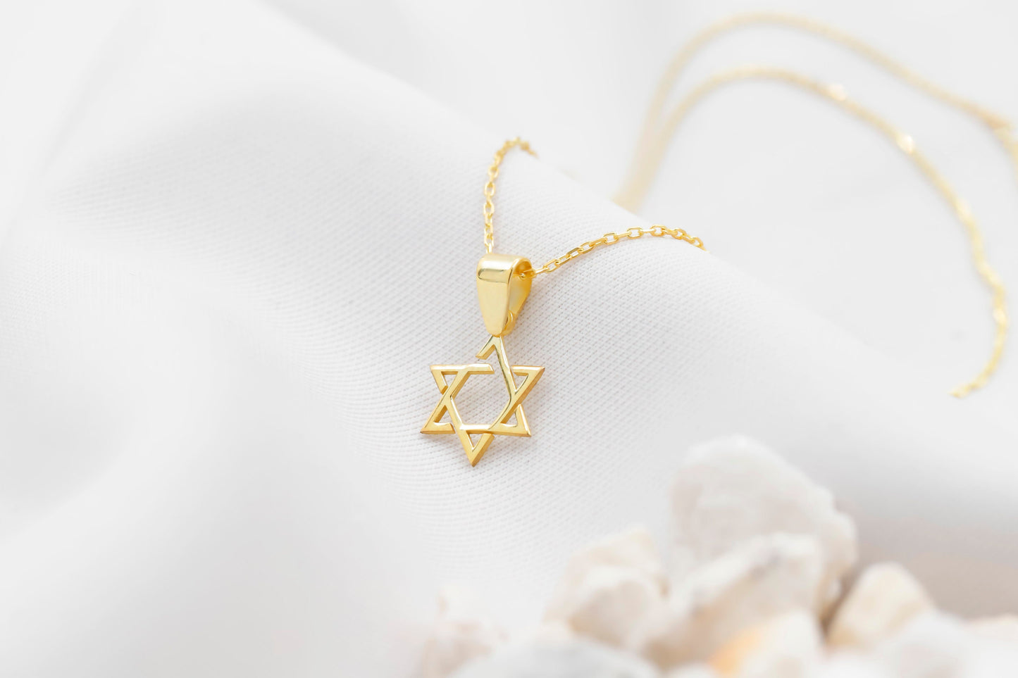 Gold necklace with a Star of David pendant on a light background
