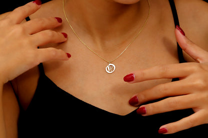 A close-up image of a woman wearing a sterling silver necklace with a gothic style initial pendant.