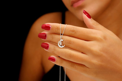 A close-up image of a woman wearing a sterling silver necklace with a gothic style initial pendant.