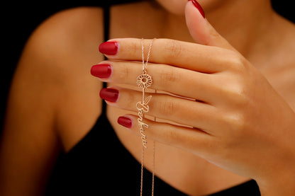 A woman wearing a black tank top showcasing a gold-filled vertical name necklace with floral designs.
