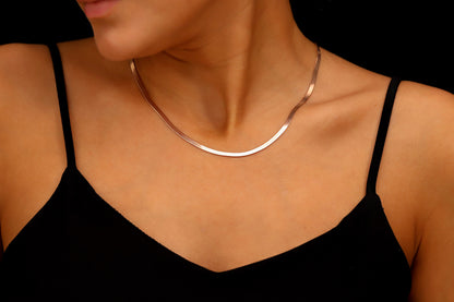 Silver necklace on a person wearing a black top against a dark background