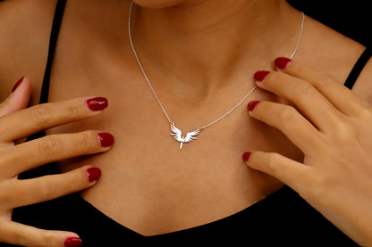 Silver necklace with a bird pendant worn by a person with red nail polish.