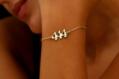 A close-up image of a person's wrist wearing a gold-colored bracelet with a specific number sequence charm.