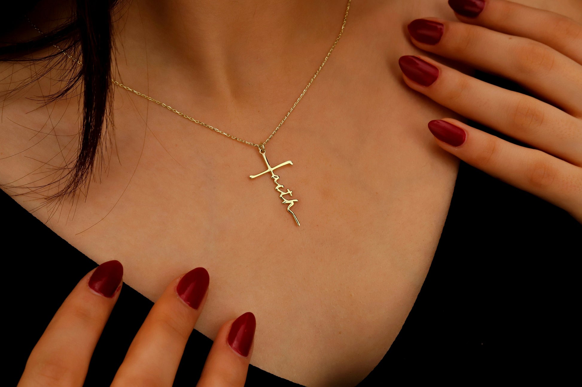 Gold necklace with 'Faith' pendant on a person's neck, with hands touching the necklace.