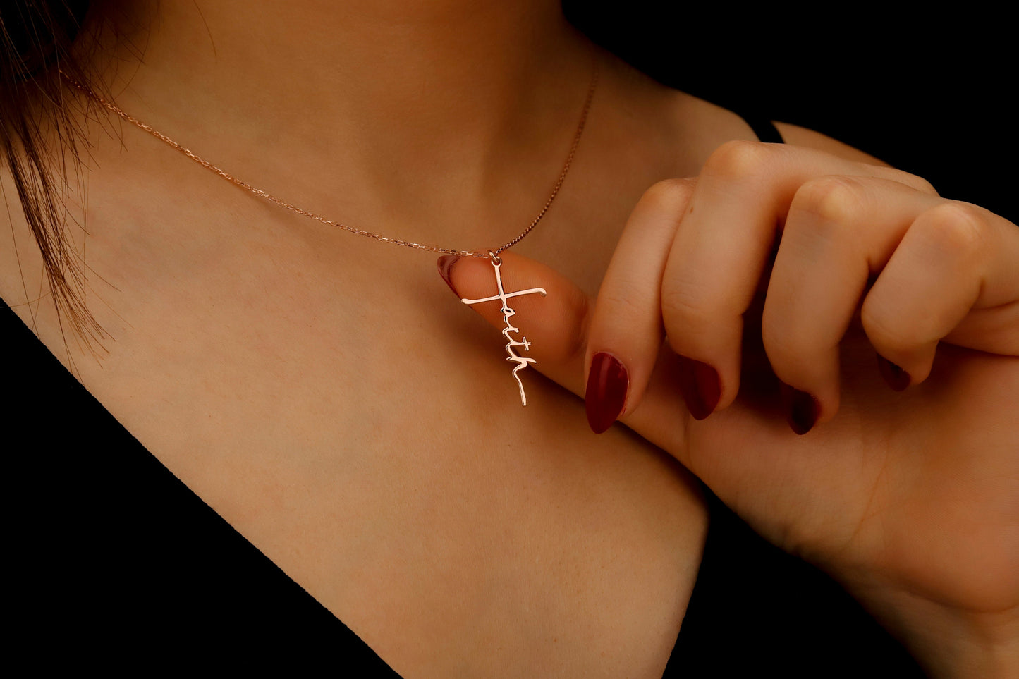 Necklace with a cross pendant being adjusted on a person's neck against a dark background