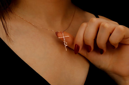 Necklace with a cross pendant being adjusted on a person's neck against a dark background