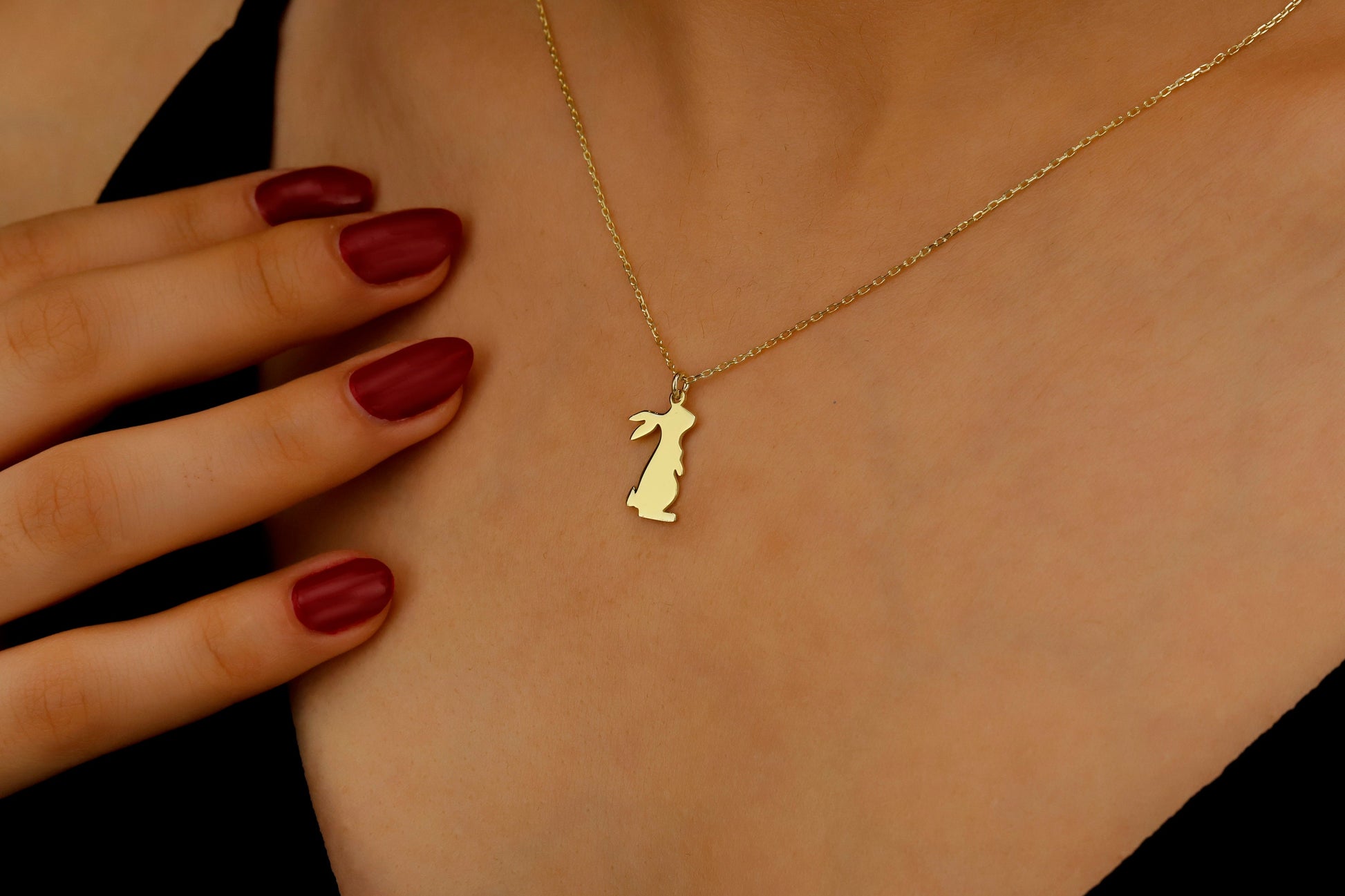 Gold necklace with a pendant worn by a person, close-up of the necklace on skin.