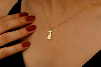 Gold necklace with a pendant worn by a person, close-up of the necklace on skin.