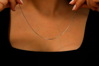 A close-up image of a sterling silver box chain necklace with delicate layered chains, displayed on a person's neck.