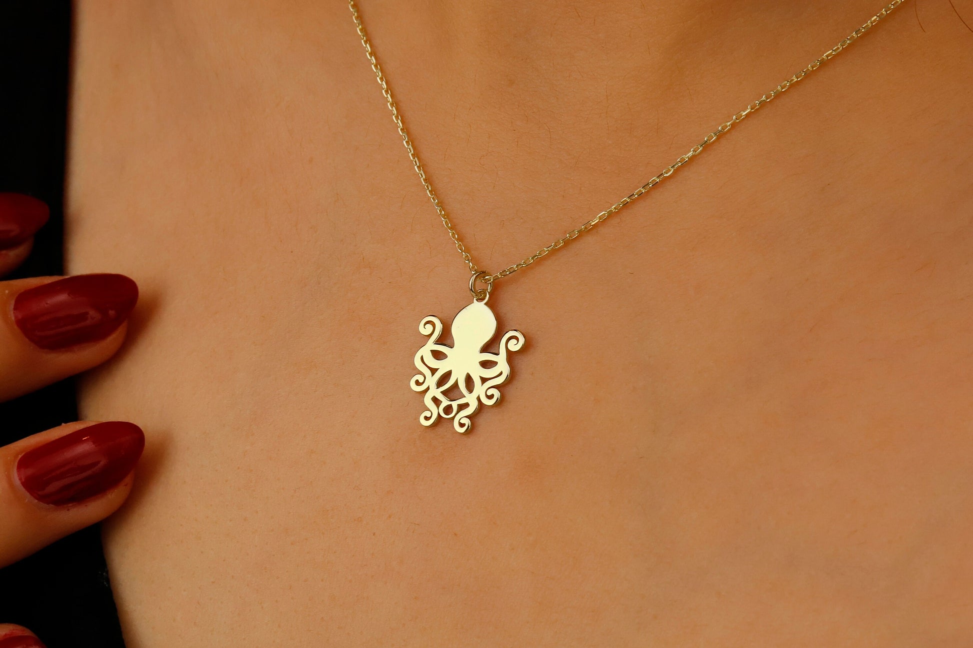 Gold octopus necklace on a person's neck with a blurred background