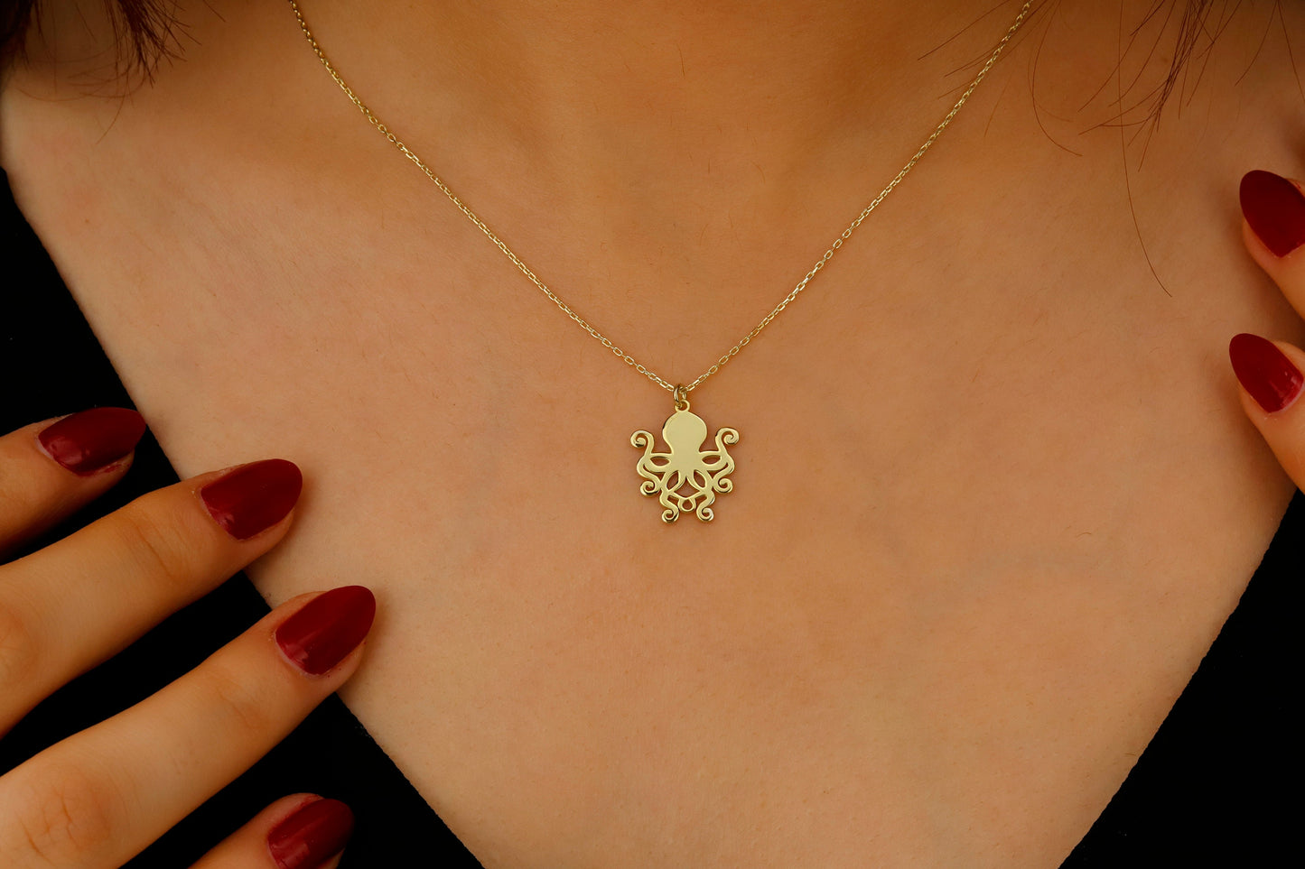 Gold necklace with an octopus pendant on a person's neck, close-up shot.
