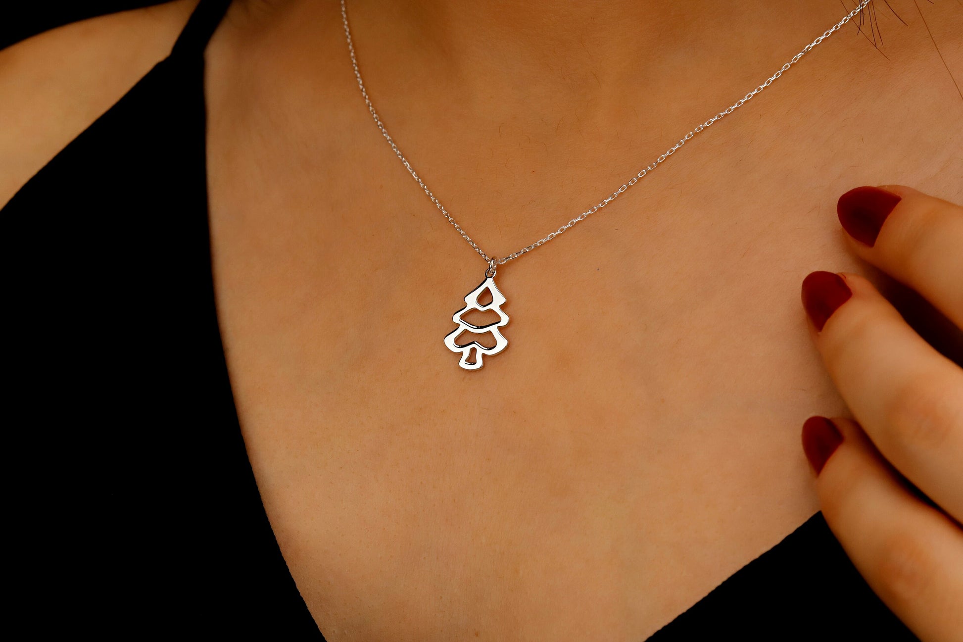 Silver necklace with a tree pendant on a person's neck