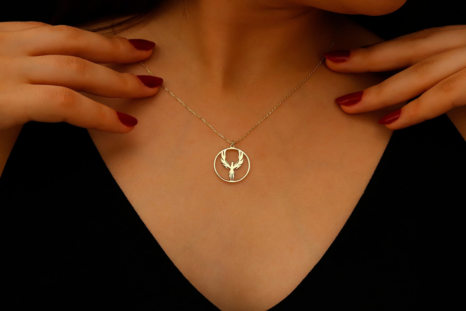 Gold necklace with a deer pendant worn by a person against a black background