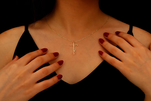 Person wearing a gold necklace with a cross pendant, hands touching chest.