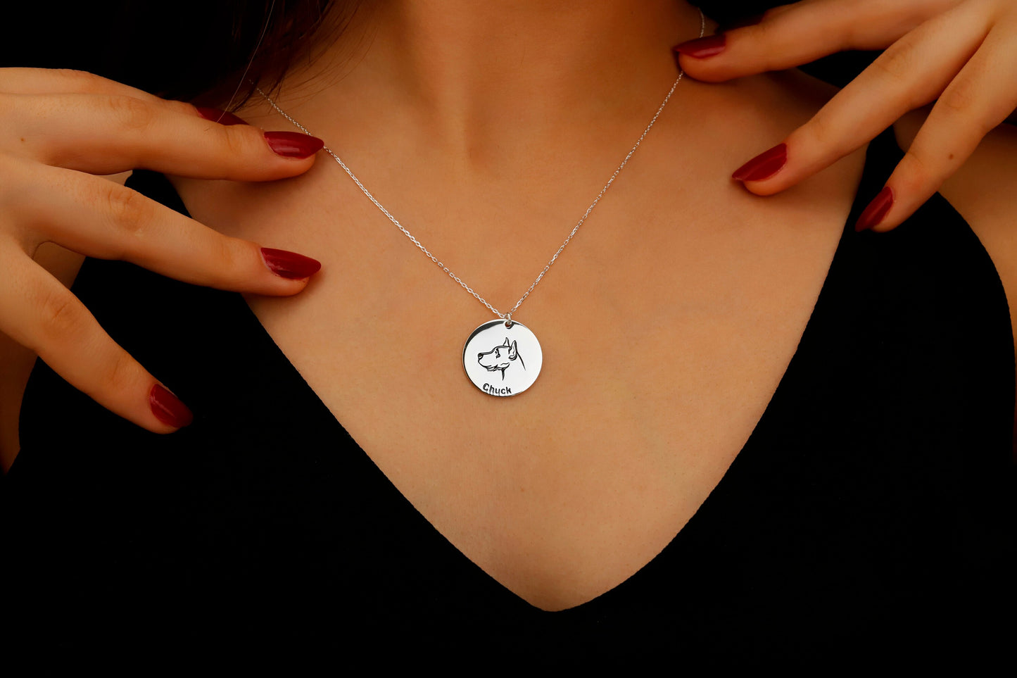 Necklace with a round pendant featuring an engraved design, worn by a person.
