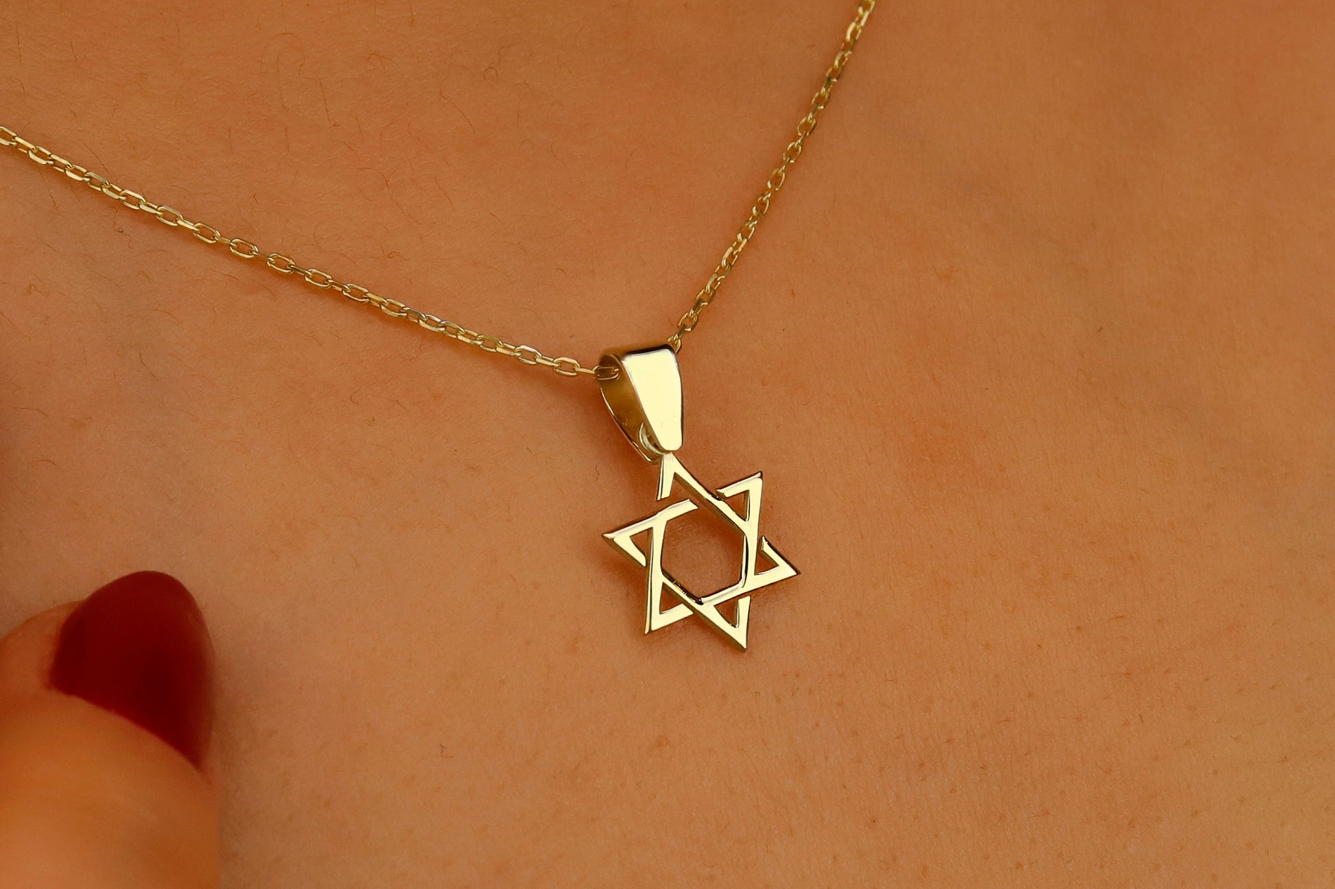 Gold necklace with a Star of David pendant on a skin background