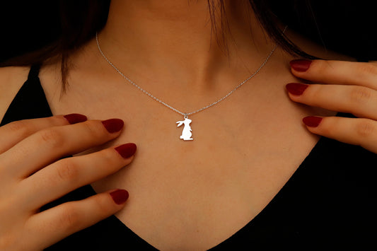 Necklace with a pendant worn by a person, with hands adjusting it.