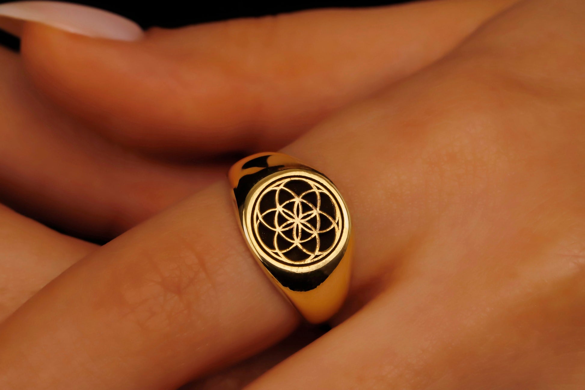 Gold ring with a black symbol on a person's finger