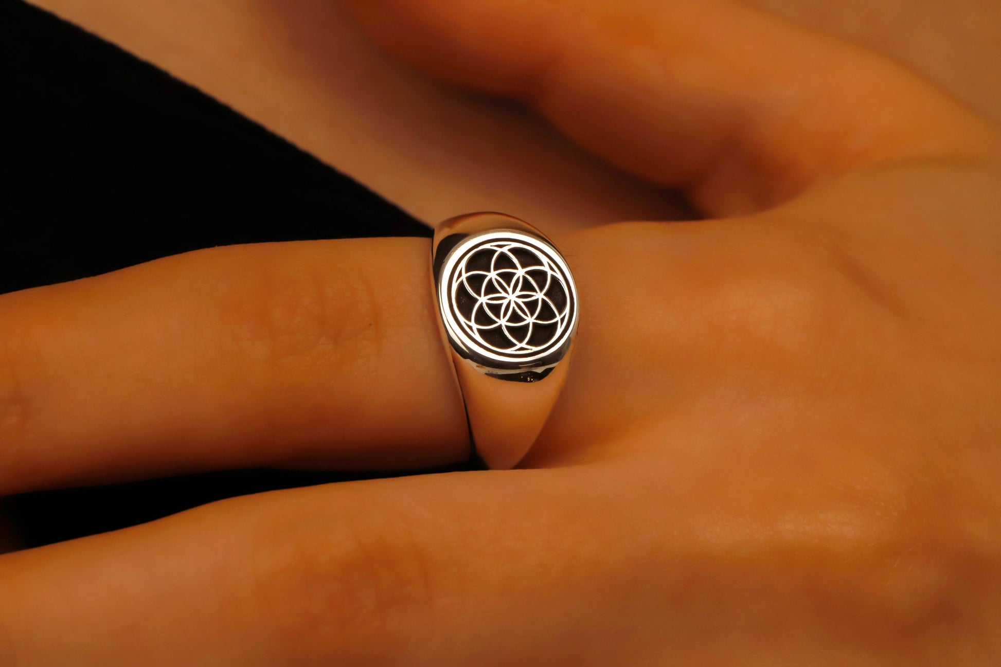 Silver ring with a symbol on a person's finger