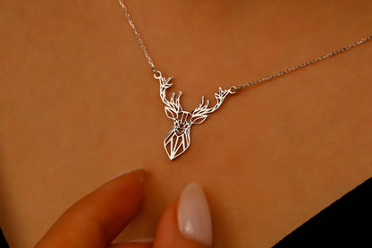 Silver deer-shaped necklace on a beige background