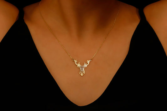 Gold deer necklace on a mannequin neck against a black background