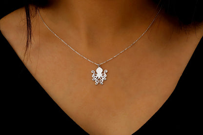 Silver octopus pendant necklace on a person's neck against a dark background