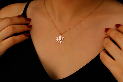 Silver octopus pendant necklace on a person's neck with hands adjusting it.