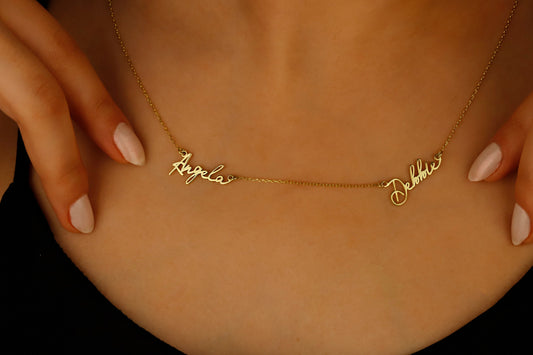 A close-up image of a custom two-name necklace made of 14K gold filled, featuring the names in a cursive script.