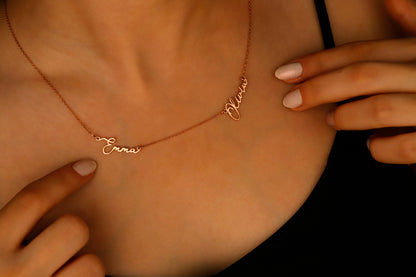 A close-up image of a custom two-name necklace made of 14K gold filled, featuring the names in a cursive script.