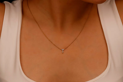 Gold necklace with a small pendant on a person wearing a white top.