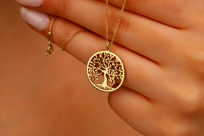 A woman's hands adjusting a delicate necklace with a Tree of Life pendant 