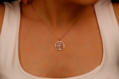 a delicate necklace with a Tree of Life pendant on a person's neck.