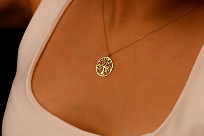  a delicate necklace with a Tree of Life pendant on a person's neck.