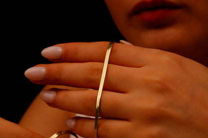 A close-up image of a person wearing a 14K gold herringbone snake chain necklace.