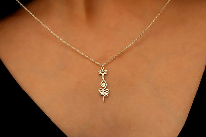 Gold necklace with a leaf-shaped pendant on a person's neck against a black background