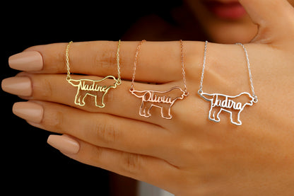 A woman is seen from the shoulders up, wearing a custom dog name necklace with a pet silhouette design. The necklace is gold-colored, and the pendant features a dog's silhouette with a letter.