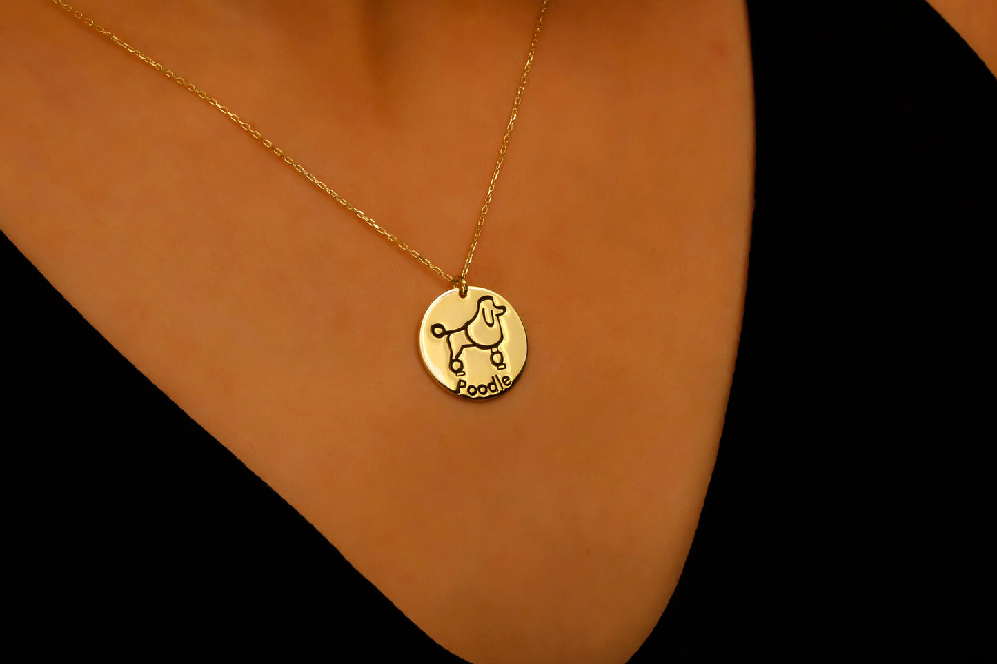 Gold necklace with a pendant on a person's neck against a black background