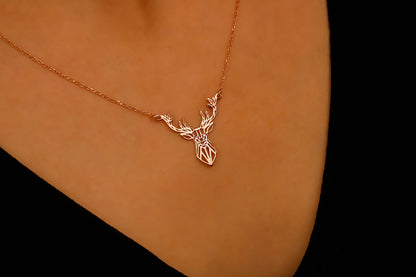 Gold necklace with a deer pendant on a person's neck against a black background